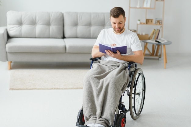 Homme en fauteuil roulant lisant un livre à la maison