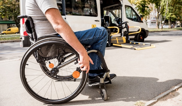 Un homme en fauteuil roulant se déplace vers l'ascenseur d'un véhicule spécialisé