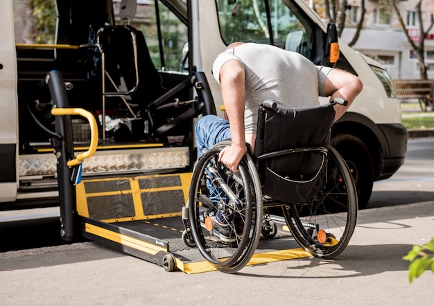 Un homme en fauteuil roulant se déplace vers l'ascenseur d'un véhicule spécialisé