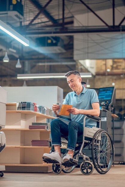 Homme en fauteuil roulant sortant une carte postale de l'enveloppe