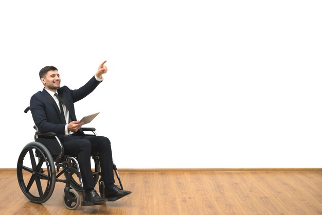 L'homme en fauteuil roulant avec une tablette faisant des gestes sur le fond du mur blanc