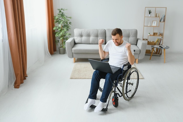 Homme en fauteuil roulant travaillant sur un ordinateur portable dans le salon