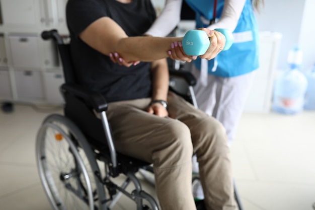 Homme en fauteuil roulant travaille sa main avec haltère