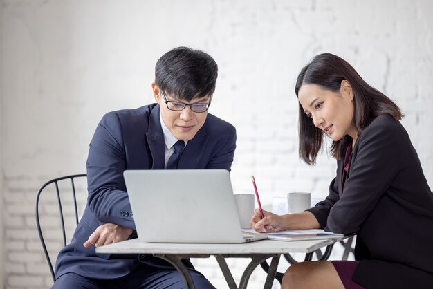 L'homme et la femme d'affaires s'asseyent à une table regardant l'ordinateur portable