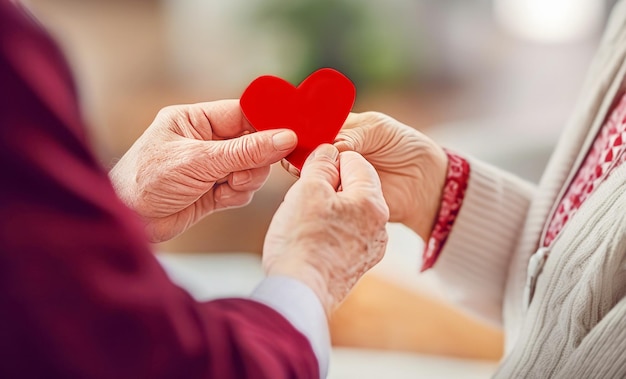 un homme et une femme âgés tiennent un cœur de papier rouge pour la fête de la Saint-Valentin.