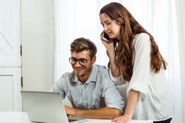 Homme et femme à l'aide d'un ordinateur portable et d'un téléphone portable au bureau