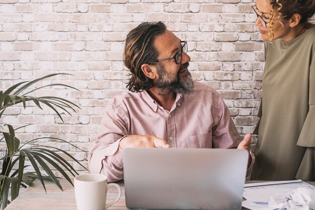 L'homme et la femme aiment travailler ensemble Les gens modernes utilisant un ordinateur portable à la maison Activité de loisirs à l'intérieur avec ordinateur et connexion Internet Un couple sourit heureux et parle d'affaires Famille et économie