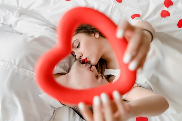 Homme et femme amoureux au lit avec des confettis en forme de coeur