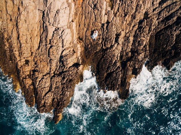 Homme et femme amoureux couché embrassant et sur la vue de dessus du bord de mer rocheux