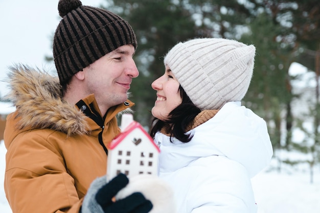 Homme et femme amoureux rendez-vous en plein air en hiver avec symbole de la maison et de l'amour. Saint Valentin, couple heureux, histoire d'amour. Nid d'amour, hypothèque, déménagement, achat, immobilier, logement pour jeune famille