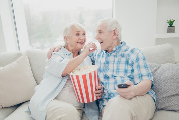 Homme et femme assis sur un canapé, manger du pop-corn