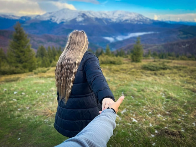 Photo un homme et une femme aux cheveux longs se tenant par la main et regardant les montagnes enneigées autour