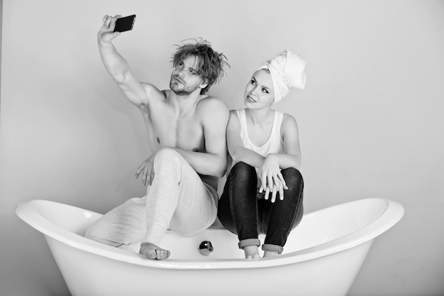 Homme et femme sur baignoire avec téléphone, couple amoureux