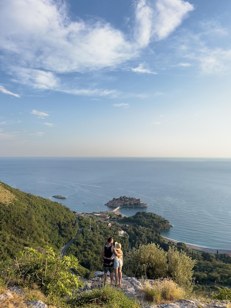 Homme et femme câlin sur une montagne surplombant l'île de sveti stefan vue arrière