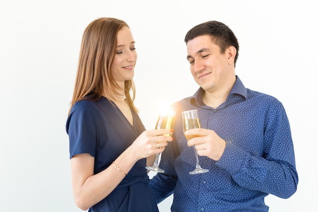 Homme et femme célébrant la fête de Noël ou du nouvel an avec des verres de champagne sur fond blanc.