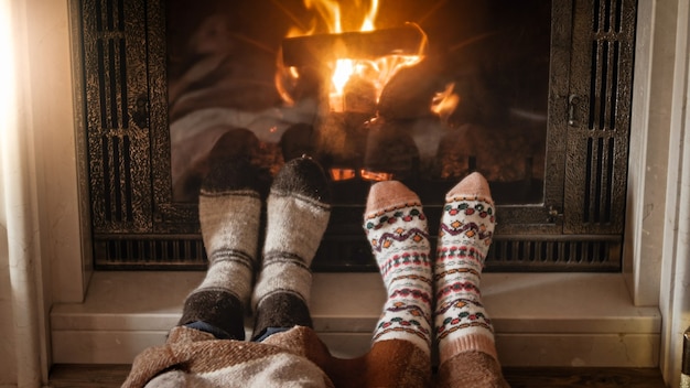 L'homme et la femme en chaussettes de laine réchauffer les pieds à la cheminée en feu