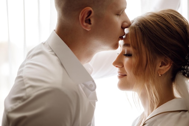 Un homme et une femme en chemise blanche s'embrassent.