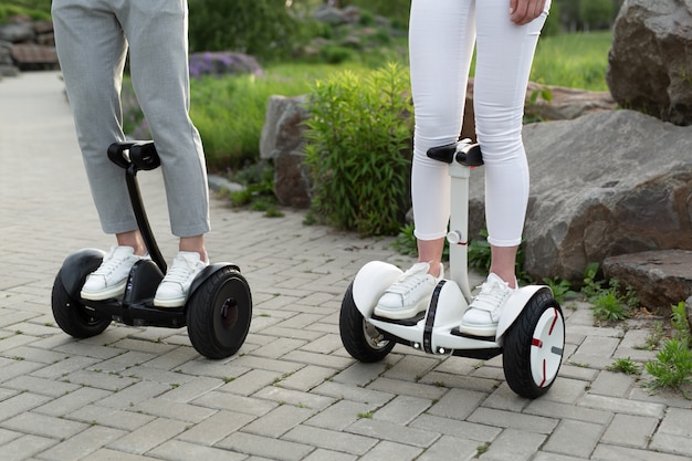 Homme et femme conduisant des scooters électriques dans un parc