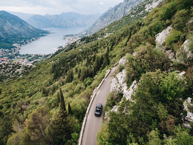 Un homme et une femme conduisent dans une voiture ouverte le long d'un sentier pittoresque dans les montagnes du Monténégro