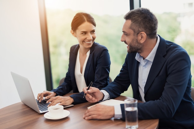 Un homme et une femme en costume d’affaires strict discutent.