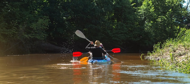 Homme et femme couple en famille kayak bateau à rames sur la rivière une randonnée aquatique une aventure estivale Tourisme écologique et extrême mode de vie actif et sain