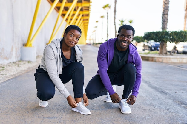 Homme et femme couple portant des vêtements de sport attachant des chaussures dans la rue