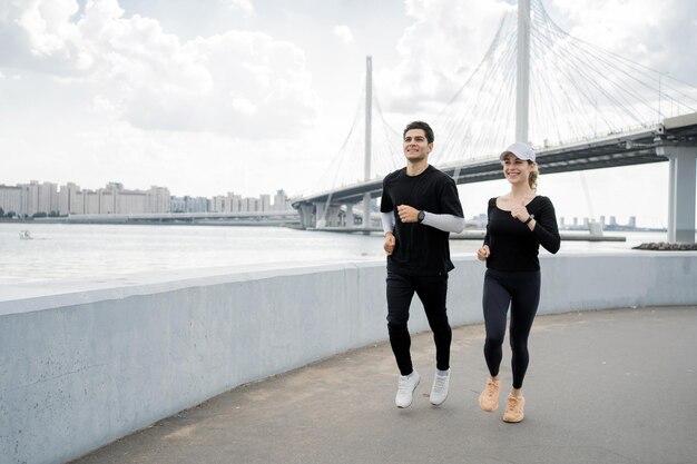 Un homme et une femme coureur faisant une séance d'entraînement active en cours d'exécution dans la ville à l'aide d'un bracelet de fitness