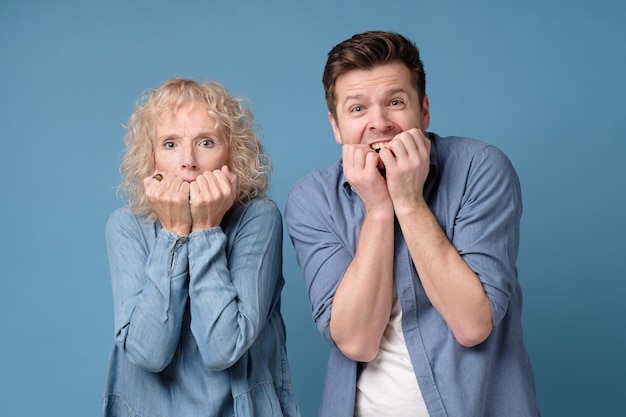 Homme et femme couvrant la bouche avec leurs mains ayant peur de se ronger les ongles