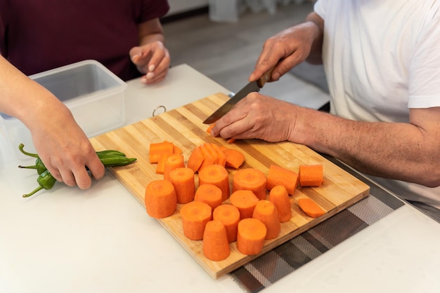 Un homme et une femme cuisinent ensemble, coupent des légumes pour un dîner végétarien.