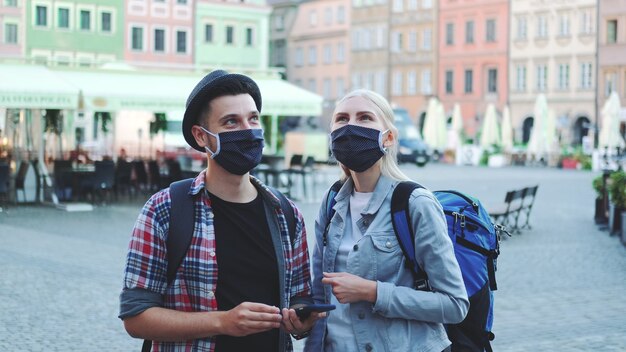 Homme et femme dans des masques de protection et avec des sacs à l'aide de smartphone