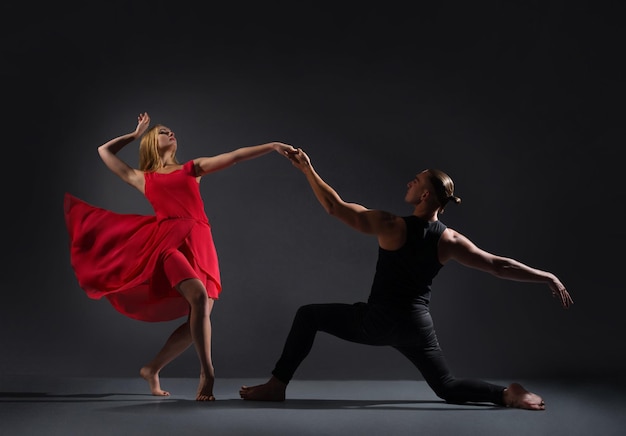 Un homme et une femme dansent des danses en couple sur un fond gris foncé Concept de relation