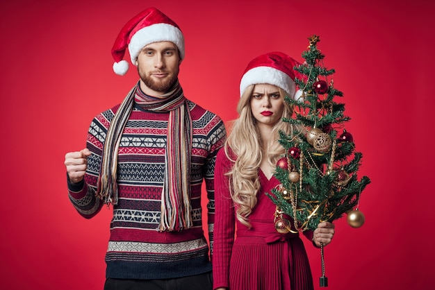 Homme et femme debout à côté de l'arbre de Noël jouets lifestyle fond rouge