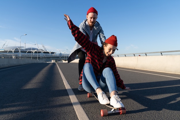 L'homme et la femme élégants patinant sur le longboard apprécient le temps ensemble la mode urbaine et l'activité à la mode