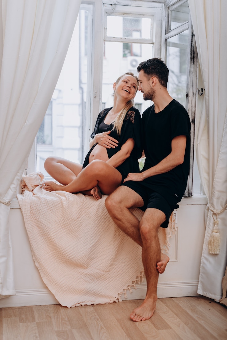 Photo un homme avec une femme enceinte posant par la fenêtre