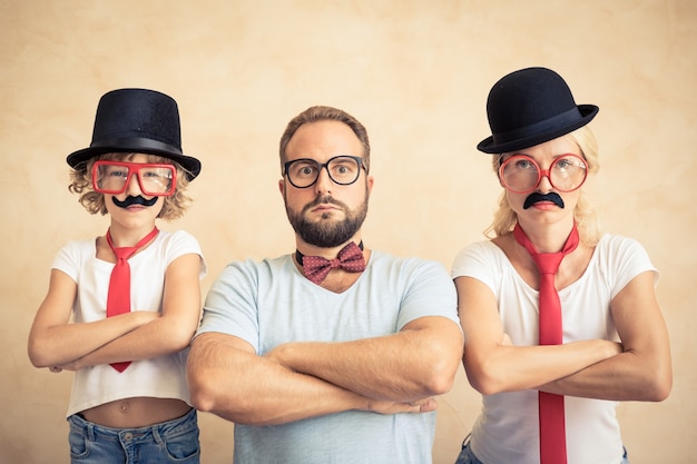 Homme, femme et enfant drôles avec une fausse moustache. Famille heureuse jouant à la maison