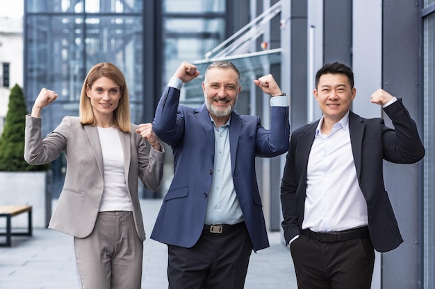 Homme et femme d'une équipe commerciale diversifiée réussie à l'extérieur d'un immeuble de bureaux souriant et regardant la caméra