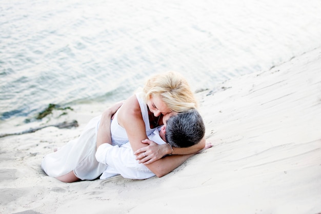 Homme et femme étreignant en position couchée sur le sable