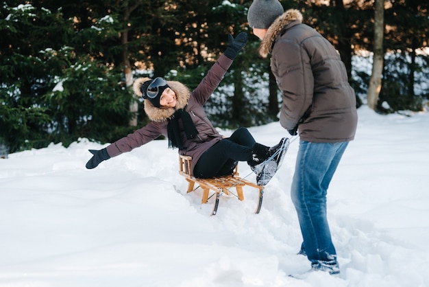 homme et femme à l'extérieur lors d'une promenade hivernale jouant aux boules de neige et à la luge