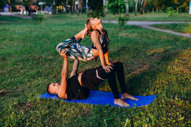 Homme et femme, faire du yoga ensemble dans le parc en plein air.