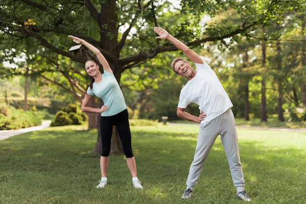 Homme et femme faisant des exercices dans le parc. Ils se réchauffent.