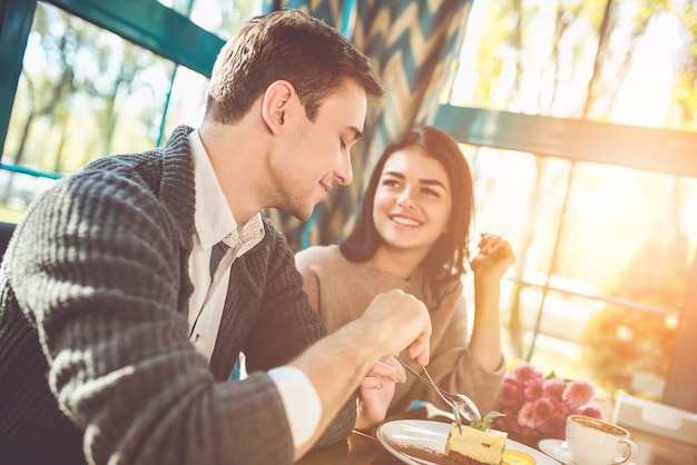 L'homme et la femme heureux mangeant un gâteau dans le café