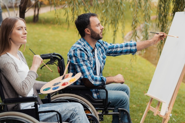 Homme et femme avec des invalides en fauteuil roulant rappellent.