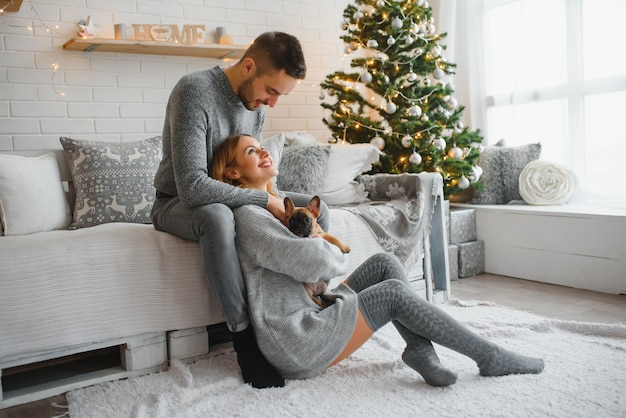 Homme et femme joyeux attrayant assis près de l'arbre de Noël étreignant