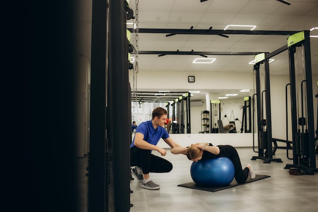 Un homme et une femme latins portant l'uniforme de physiothérapeute ayant une session de réadaptation en utilisant une balle de remise en forme au centre de réadaptation