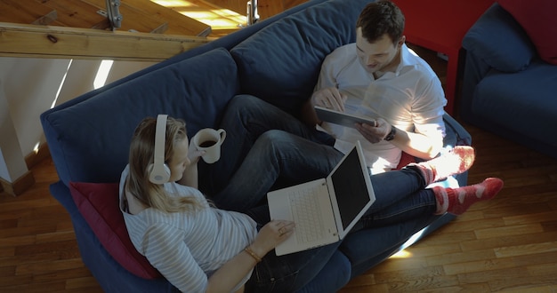 Homme et femme à la maison à l'aide d'un pad et d'un ordinateur portable