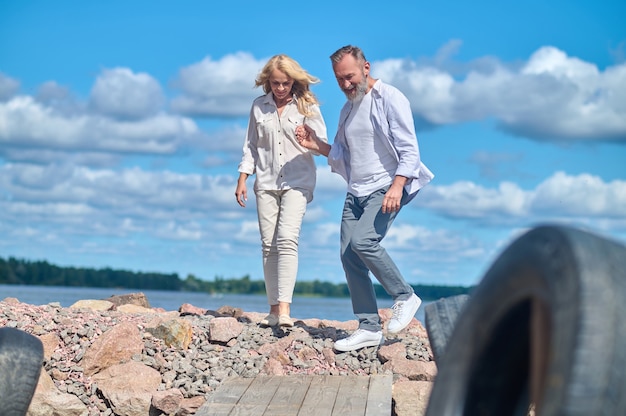 Homme et femme marchant sur des pierres près de la mer