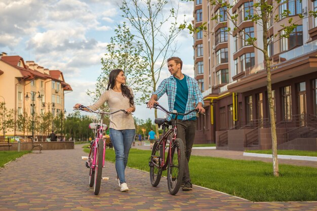 L'homme et la femme marchant avec des vélos près d'un immeuble moderne