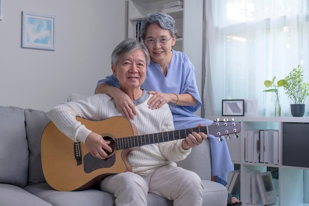 Homme et femme matures asiatiques chantant leur chanson préférée tout en jouant de la guitare à la maison