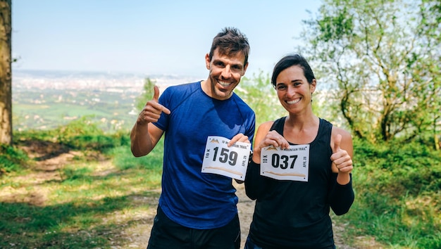 Homme et femme montrant leur numéro de trail