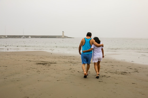 Un homme et une femme mûrs de 50 ans marchent sur une plage heureux et amoureux